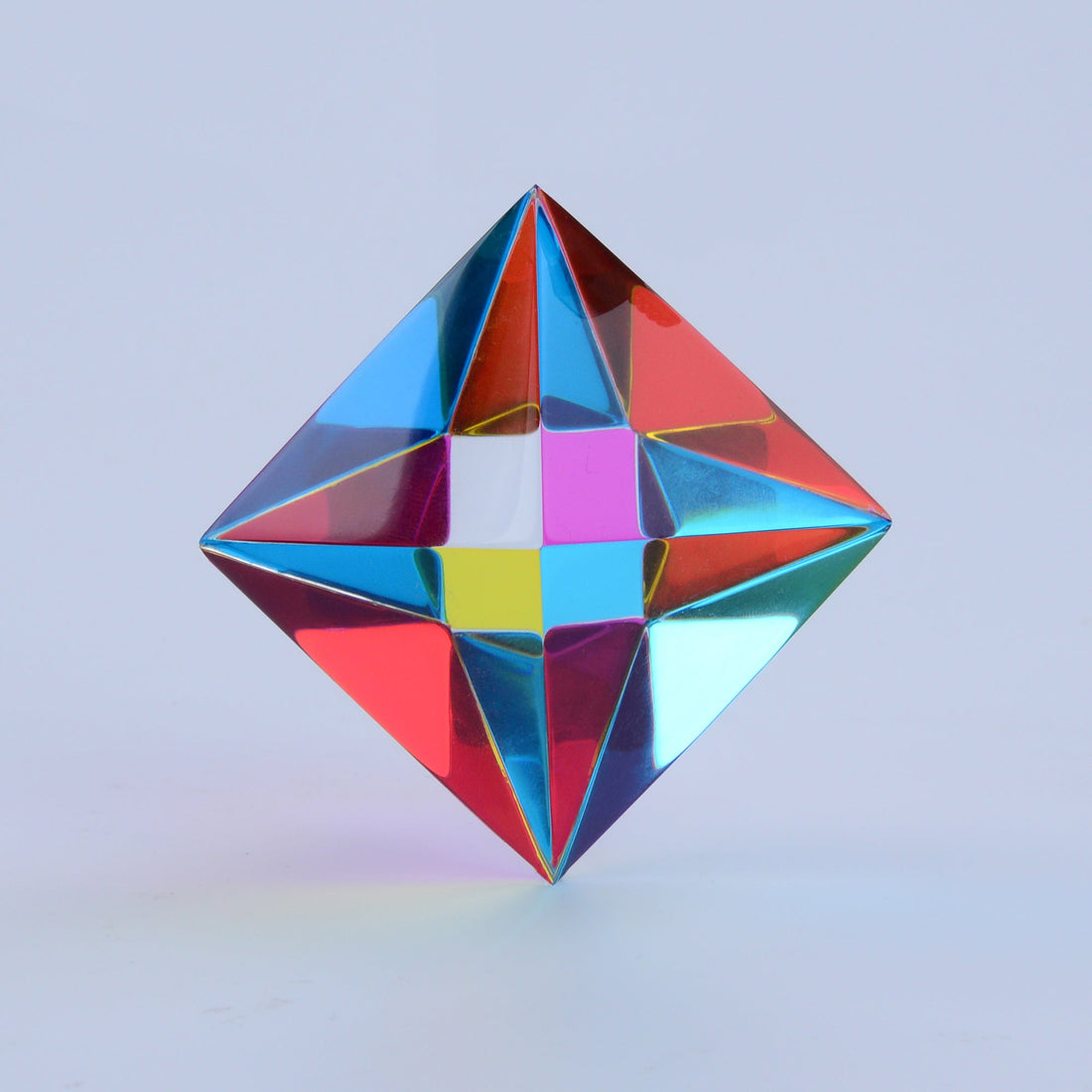 The Aether, a translucent CMY octahedron, standing on a desk in natural light